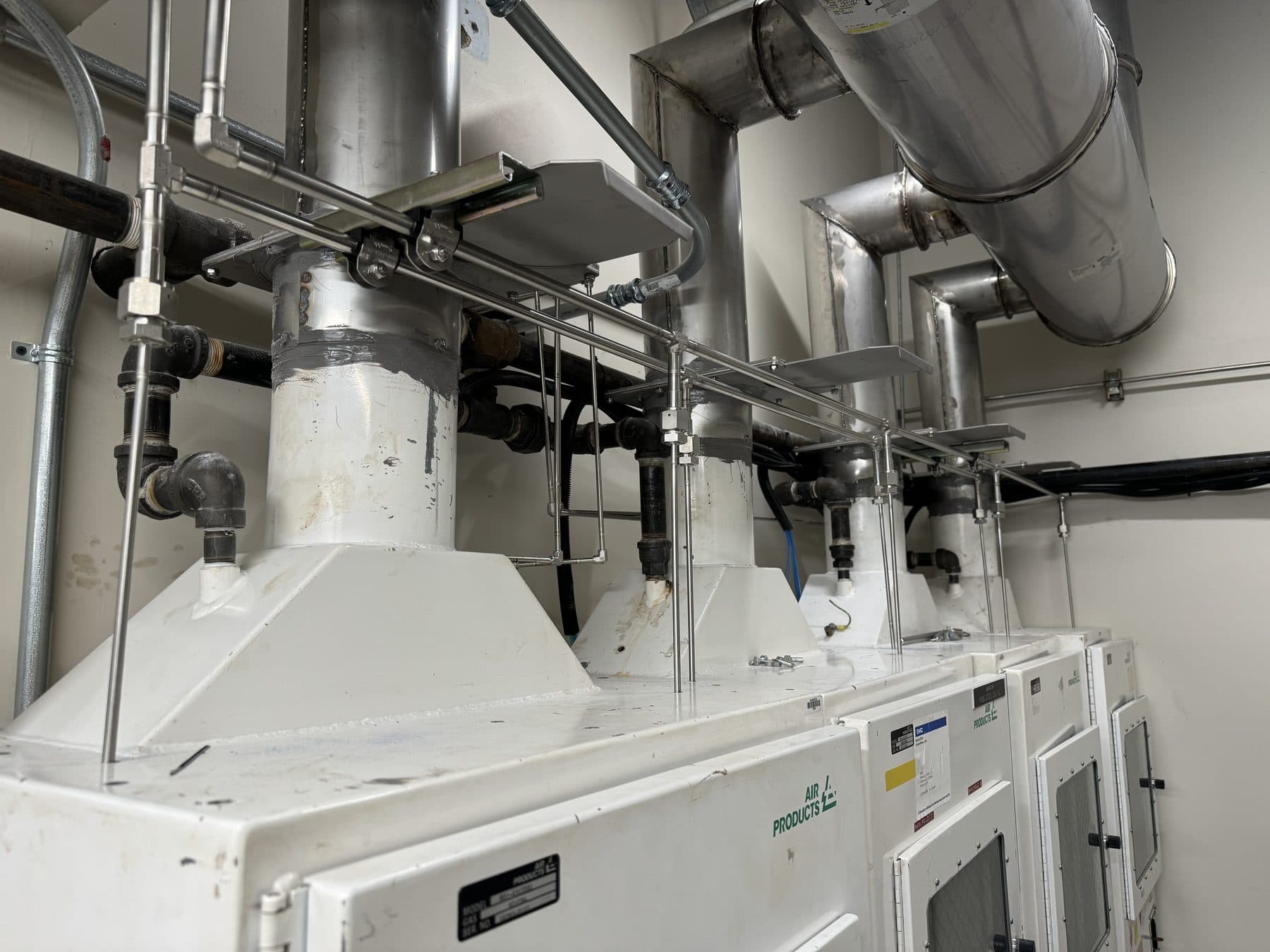 A row of exhausted gas cabinets for toxic process gases, with stainless steel exhaust ducting overhead